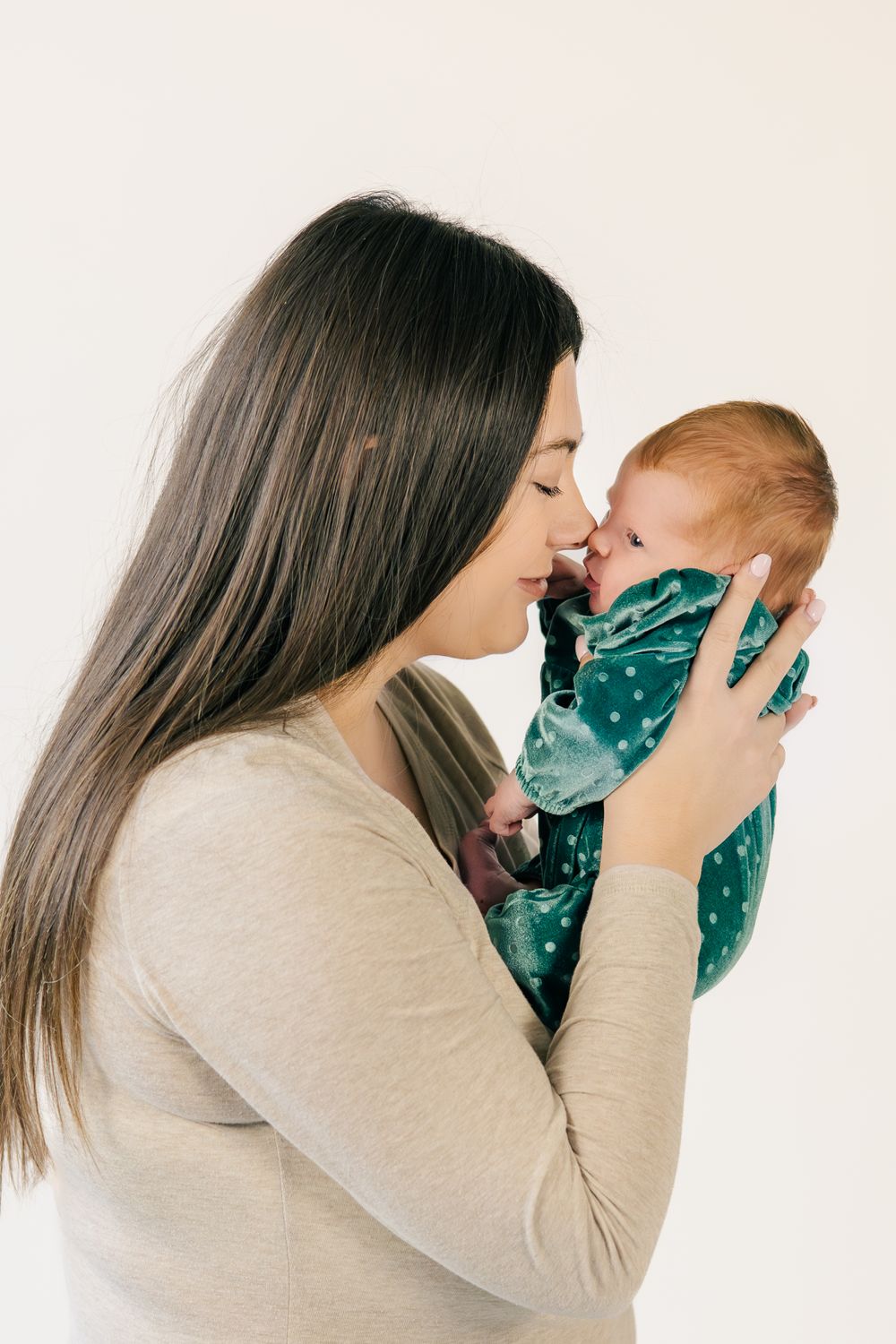 Loving moment between adult and baby in teal polka dot outfit.