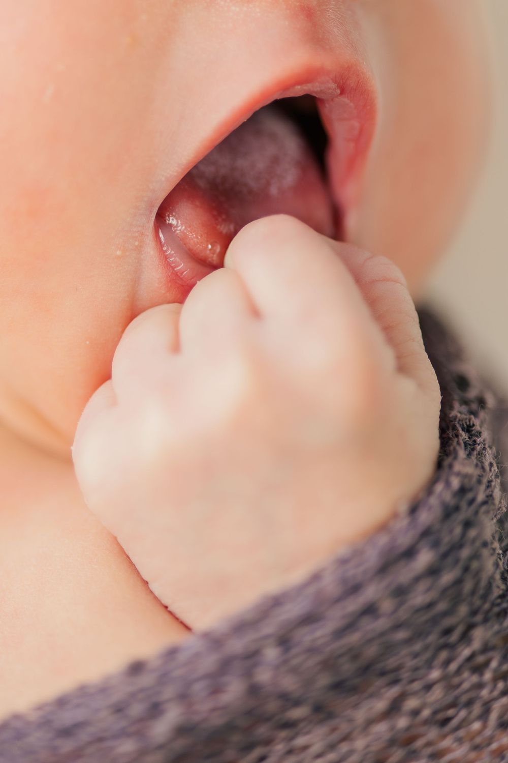 Close-up of baby's mouth with tiny fist.