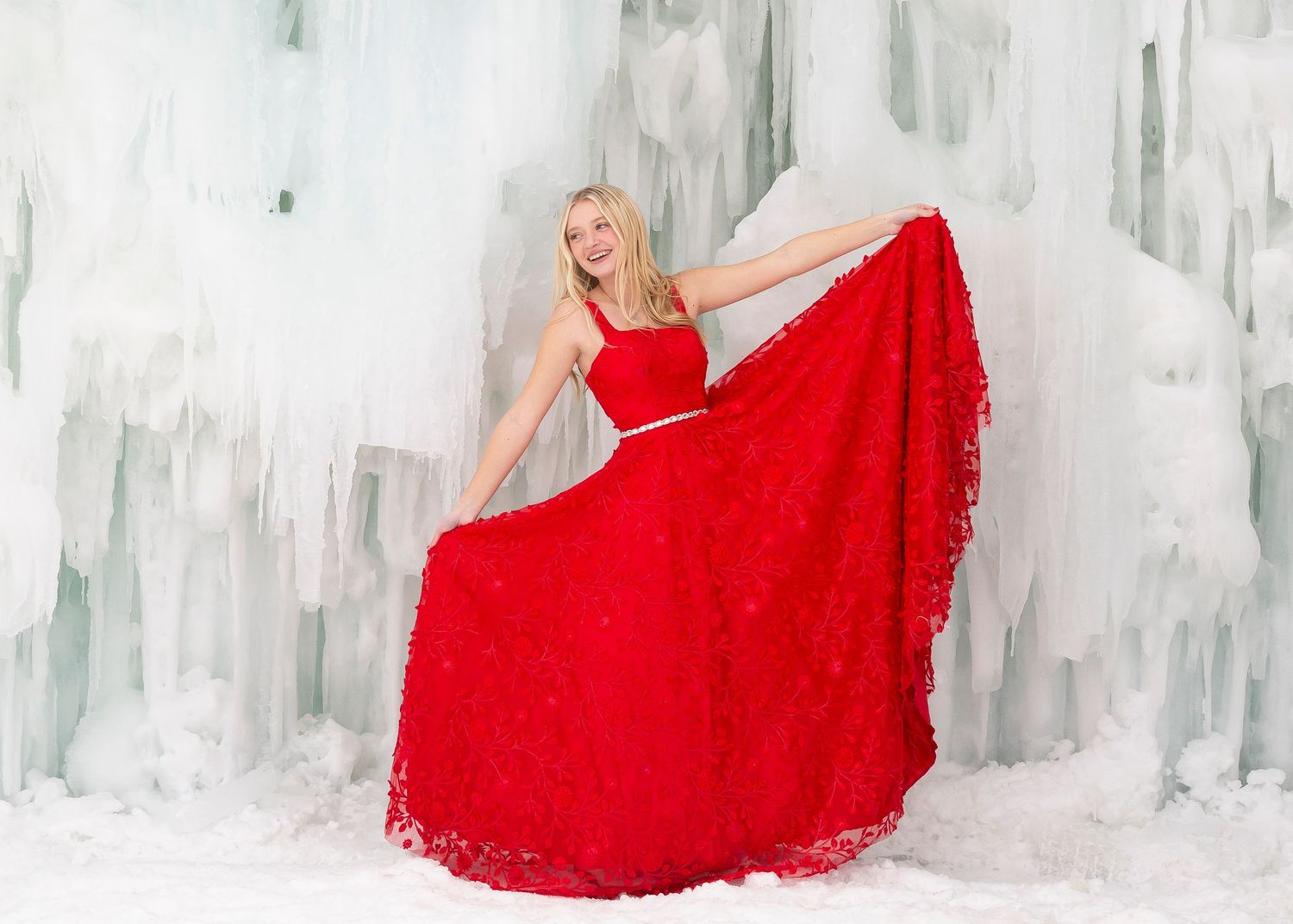 Girl in red dress posed in front of midway ice castles in utah senior portrait