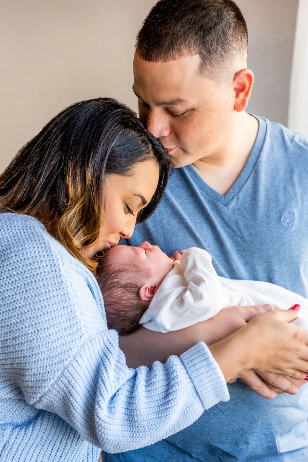 New parents cuddle their newborn baby in tender moment.