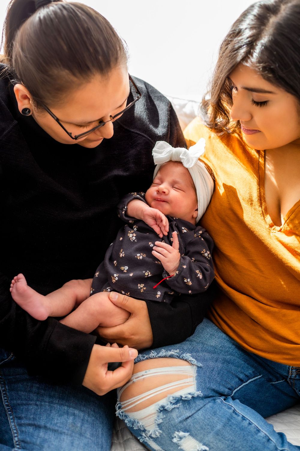 An intimate family portrait with a sleeping newborn in a floral outfit.