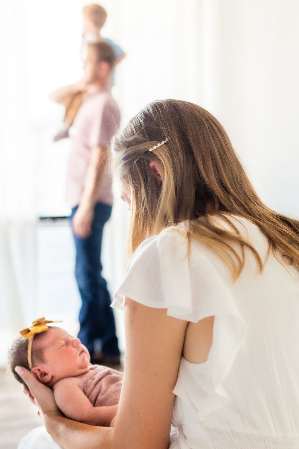 Newborn baby in pink outfit resting during indoor lifestyle photography session.