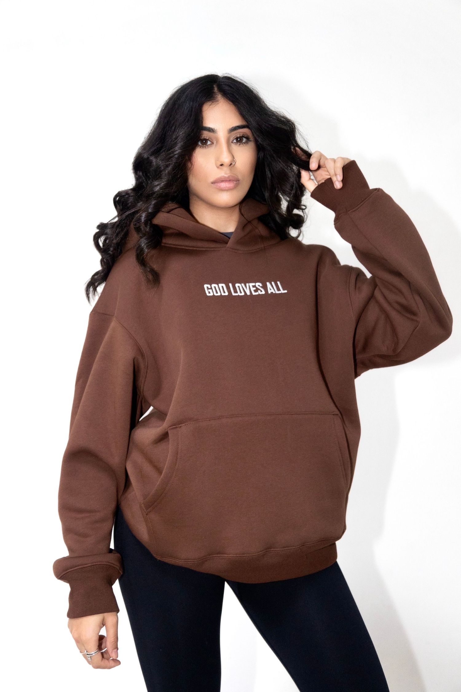 A brown hoodie sweatshirt with 'GOD LOVES ALL' text displayed on the front against a white background.