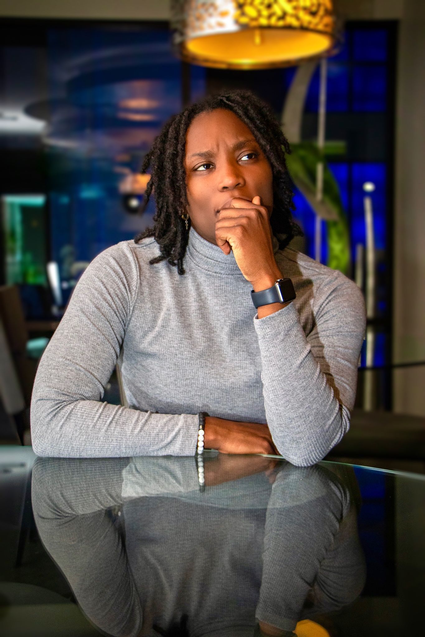 A contemplative portrait in a modern office space with colorful lighting.
