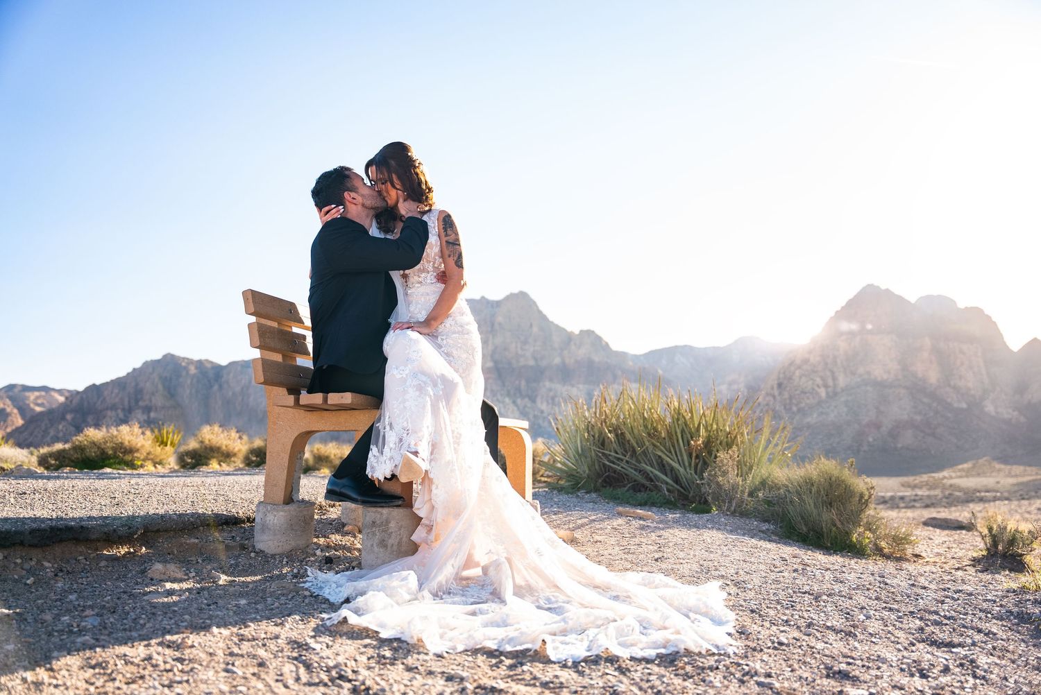 A romantic wedding photoshoot at sunset with dramatic mountain peaks in the desert background.