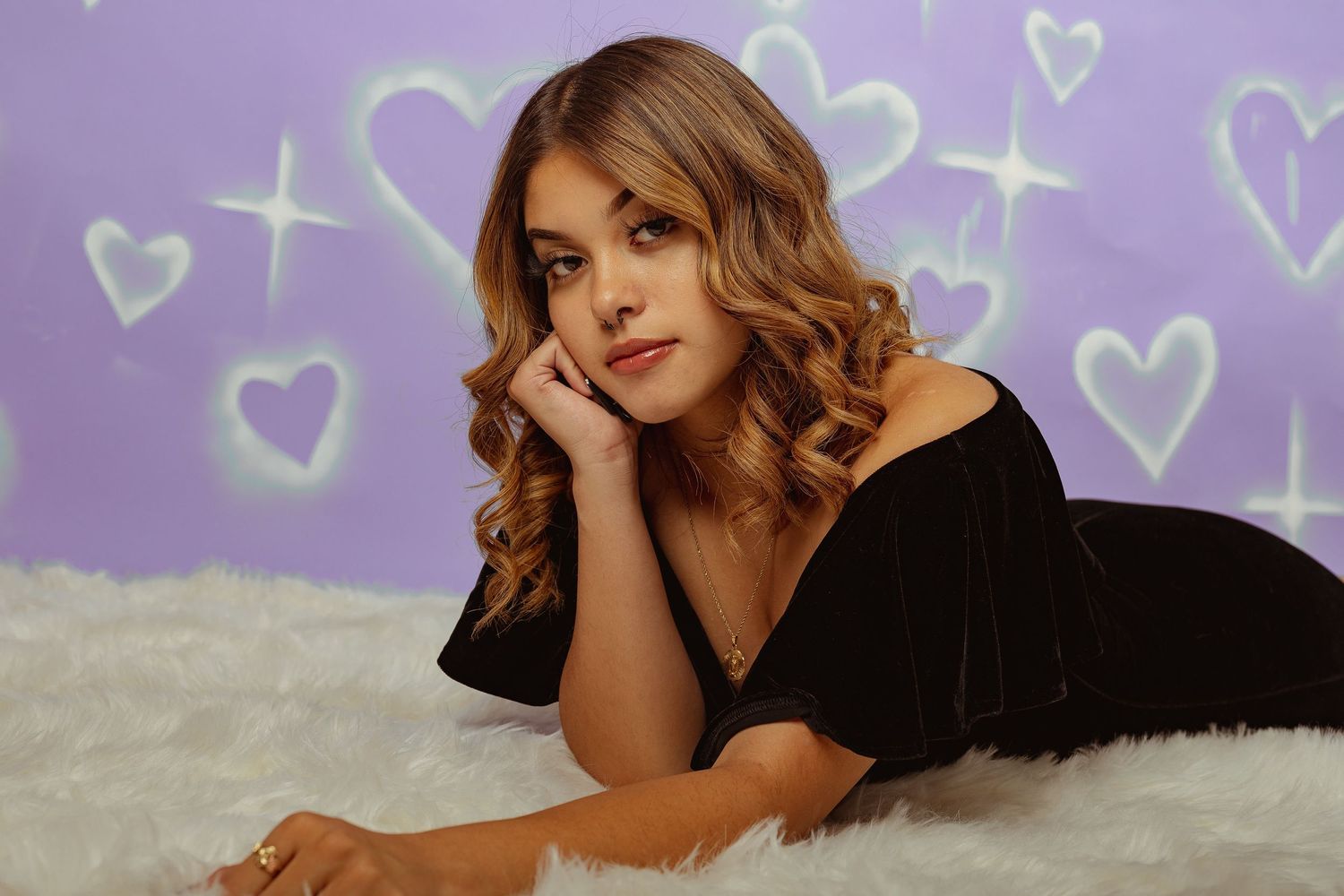 Boudoir portrait against purple background with heart decorations.