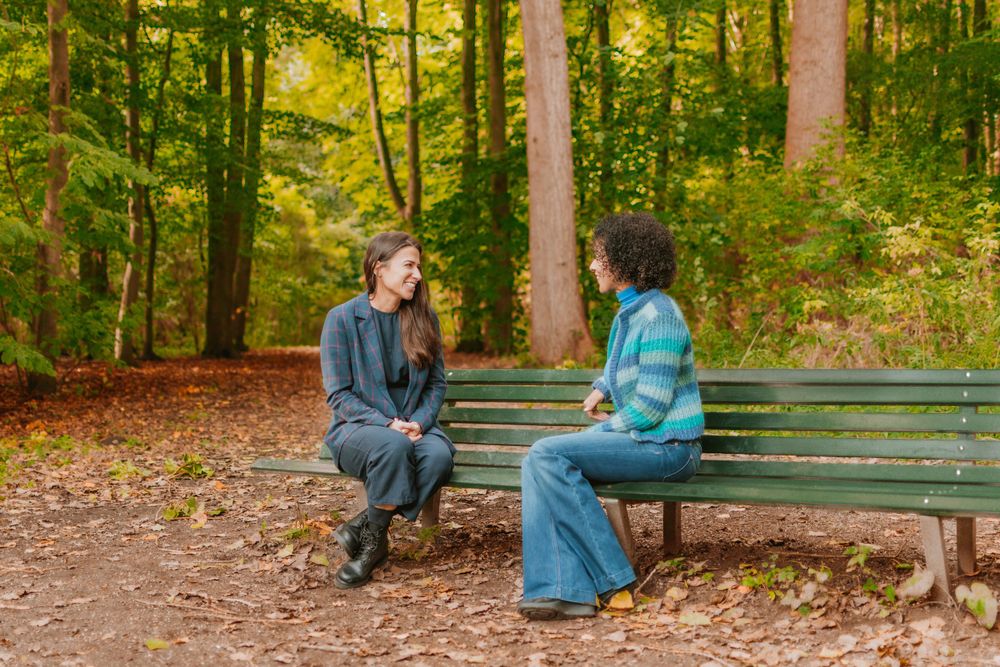 Coaching session in the forest. 2 woman talking while sitting on a bench in Amsterdamsebos.
