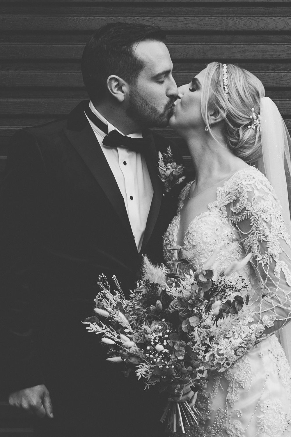 Intimate black and white portrait of newlyweds sharing a kiss.