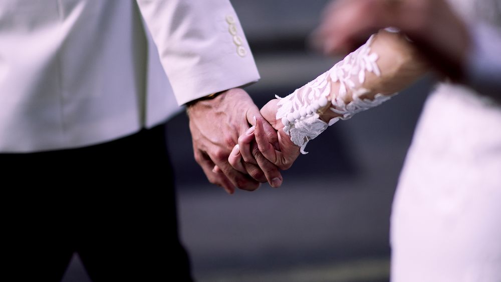 Close-up of hands with intricate henna designs holding each other.