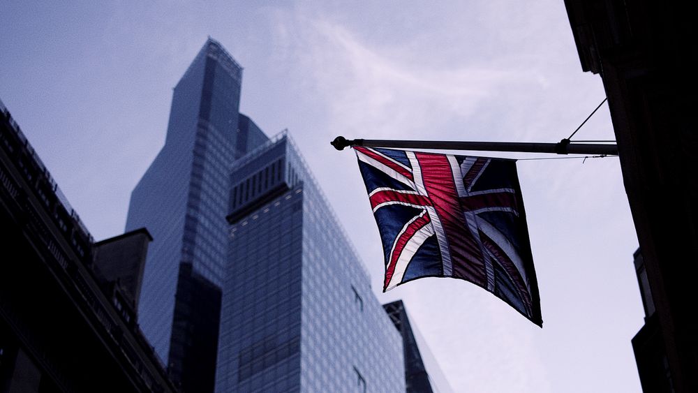 British Union Jack flag flying against modern glass skyscraper in London.