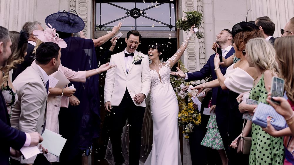 Wedding celebration with guests cheering as newlyweds exit amid joyful celebration.