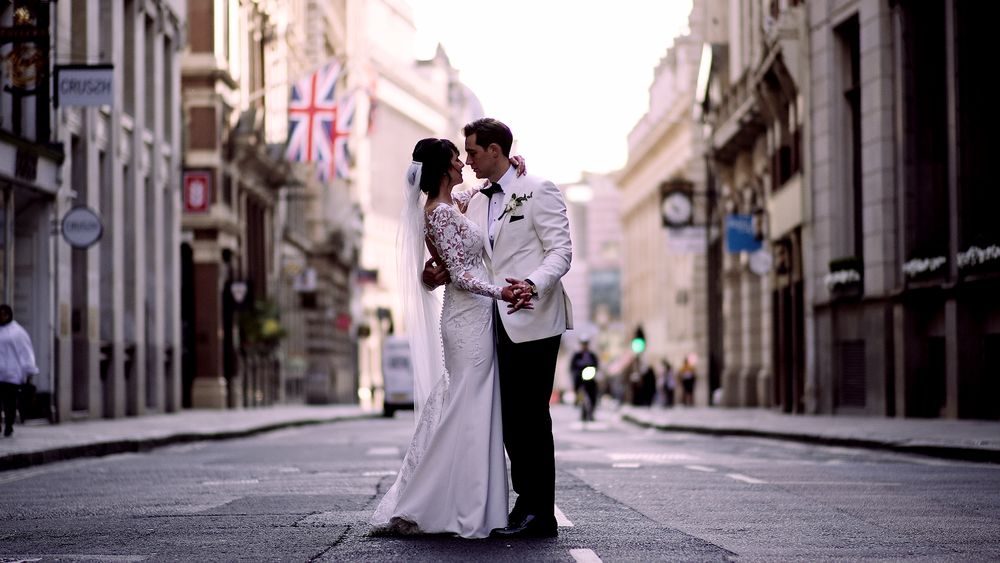 Romantic wedding portrait on an empty city street with British flag visible.