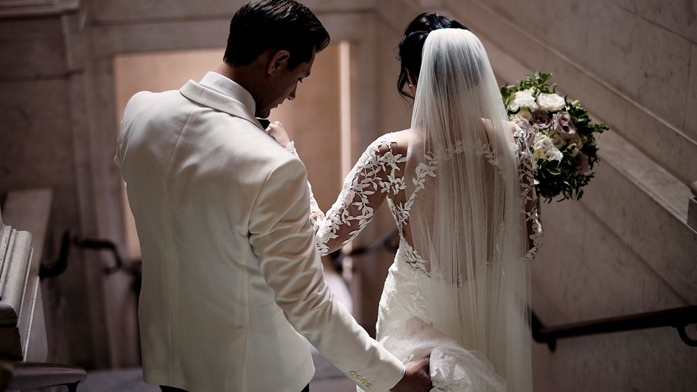 Wedding couple on stone steps with bride holding elegant white bouquet.