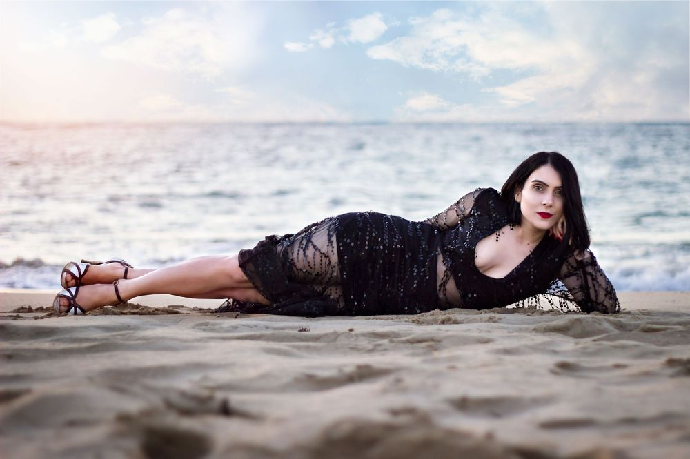 woman at Point Peron Rockingham beach in a beaded dress, laying on her side propping her head up with her hand.