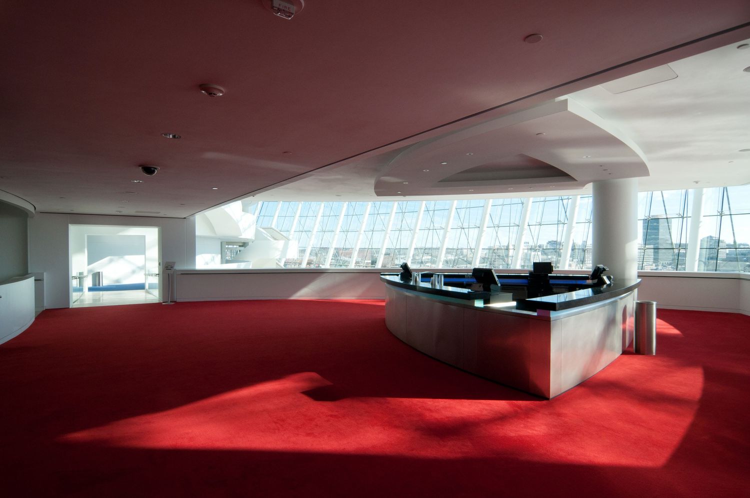 Modern office space with red carpet and curved white walls featuring large windows.