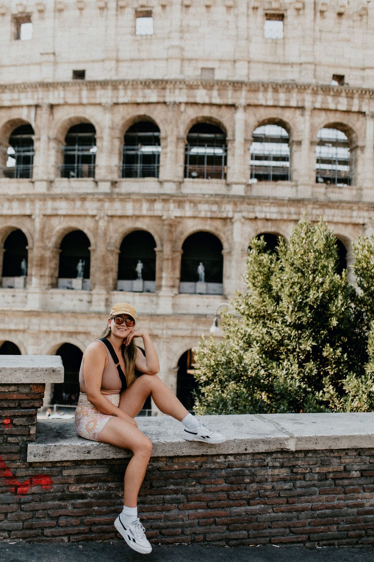 Tourist posing casually in front of the historic Roman Colosseum architecture.