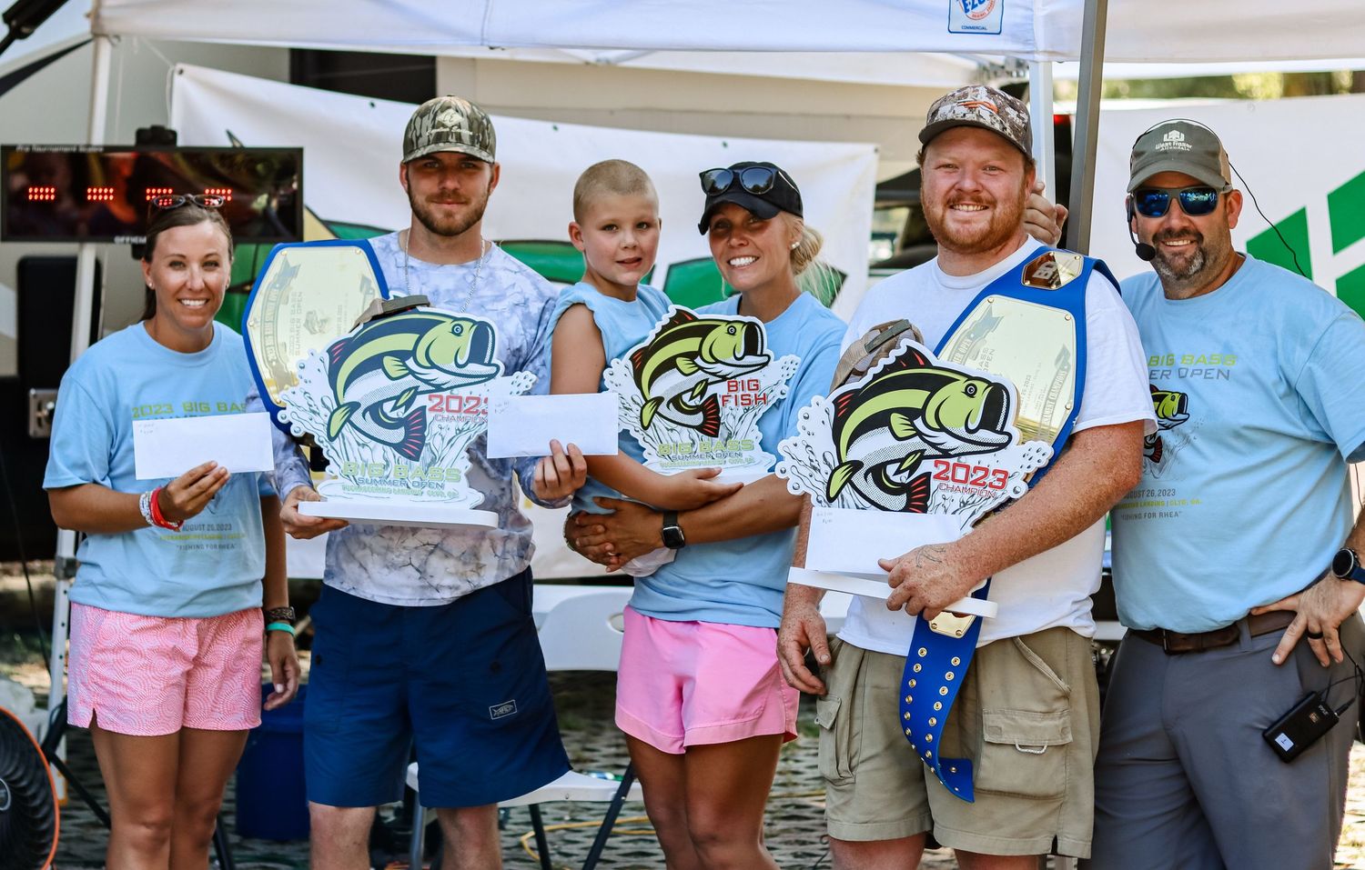 Group wearing matching blue shirts poses together at a fishing event.