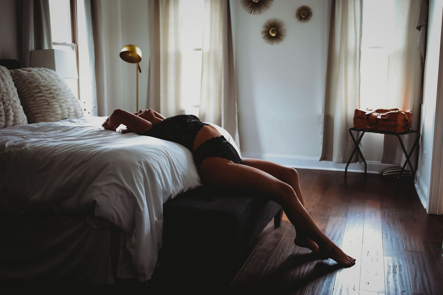 Moody boudoir photography setup in a bedroom with dramatic lighting.