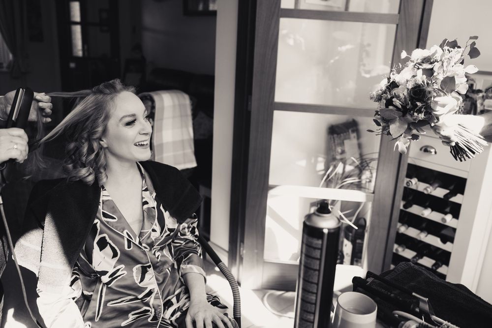 Black and white photo showing someone sitting in a patterned dress in a relaxed indoor setting with natural lighting.