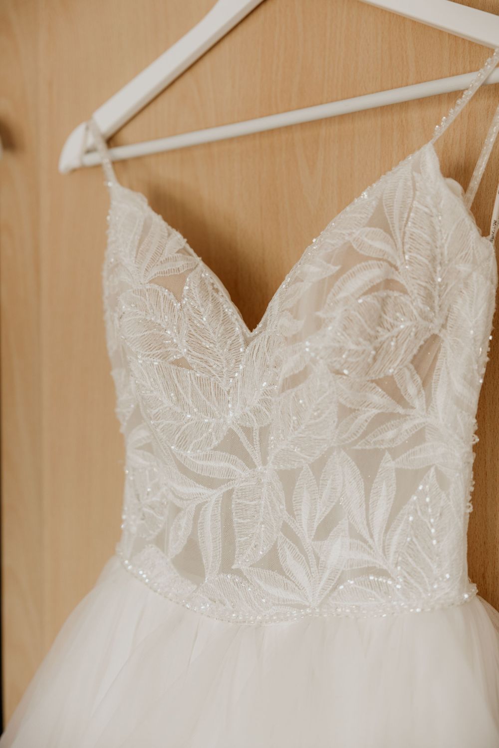 Close-up detail of intricate lace bodice on white wedding gown with sweetheart neckline.