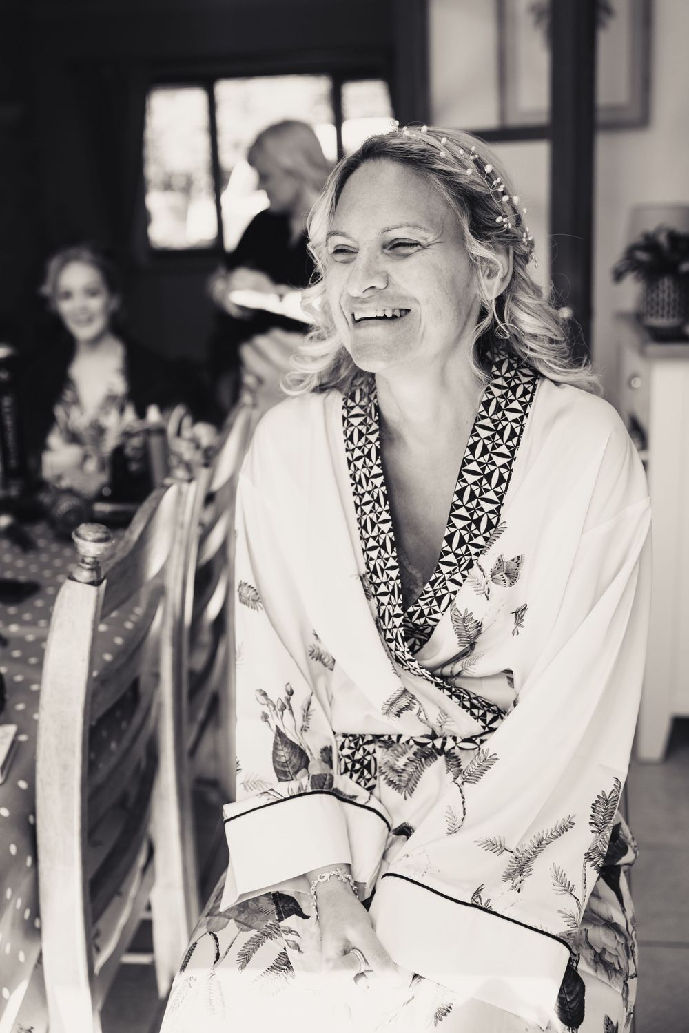 Black and white candid moment showing joyful preparation in floral robe.