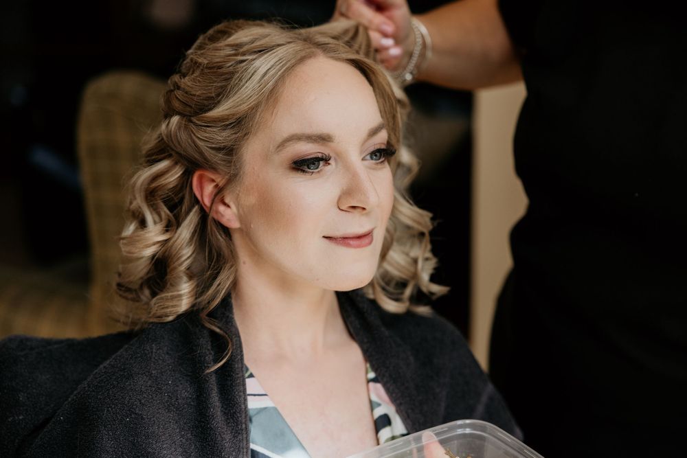 Candid pre-wedding preparation moment with elegant hair styling and makeup.