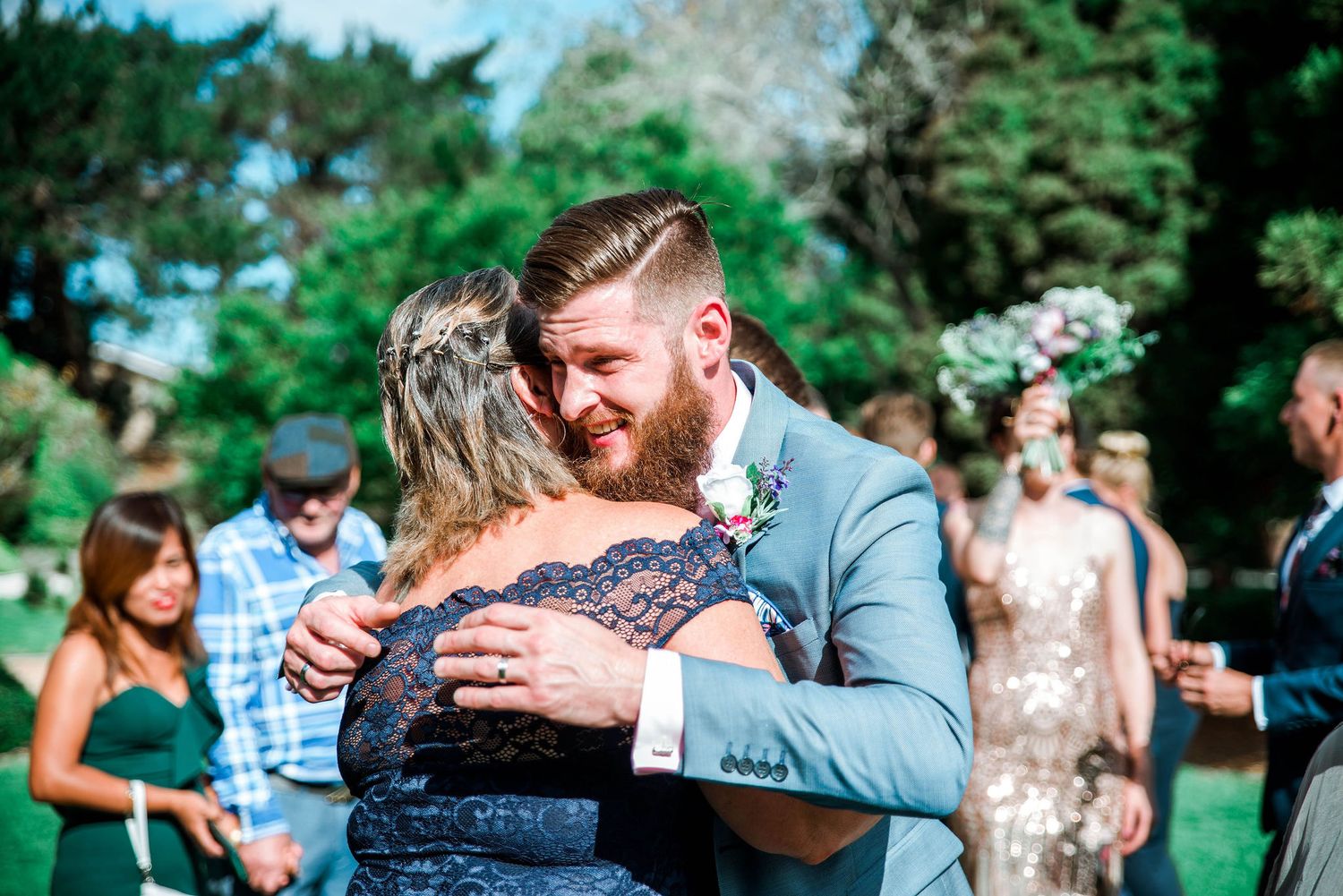 Couple dancing at outdoor wedding reception with guests watching in background.