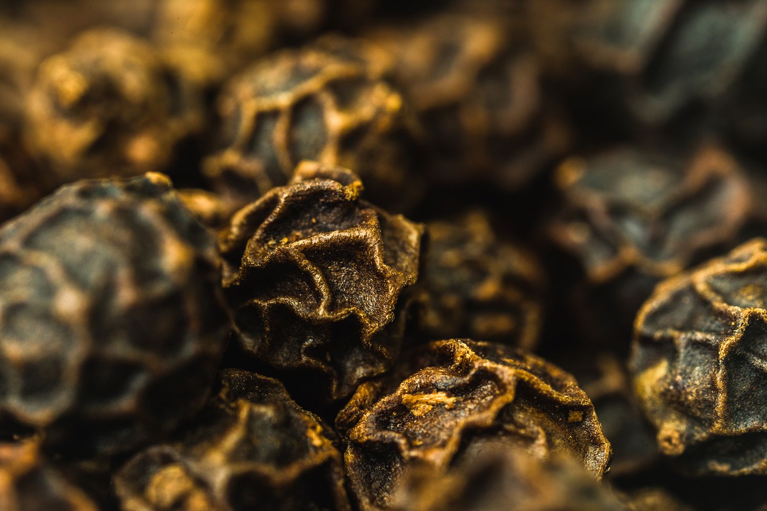 Extreme close-up of dried black peppercorns revealing intricate surface details.