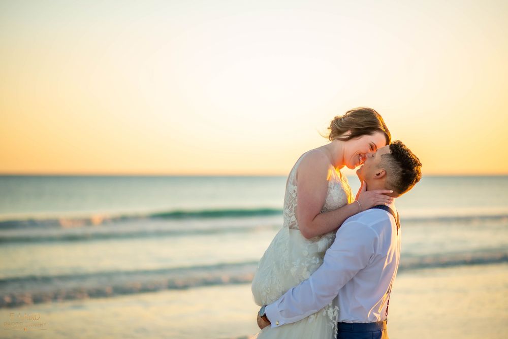 Intimate beach wedding moment at golden hour with waves in background.