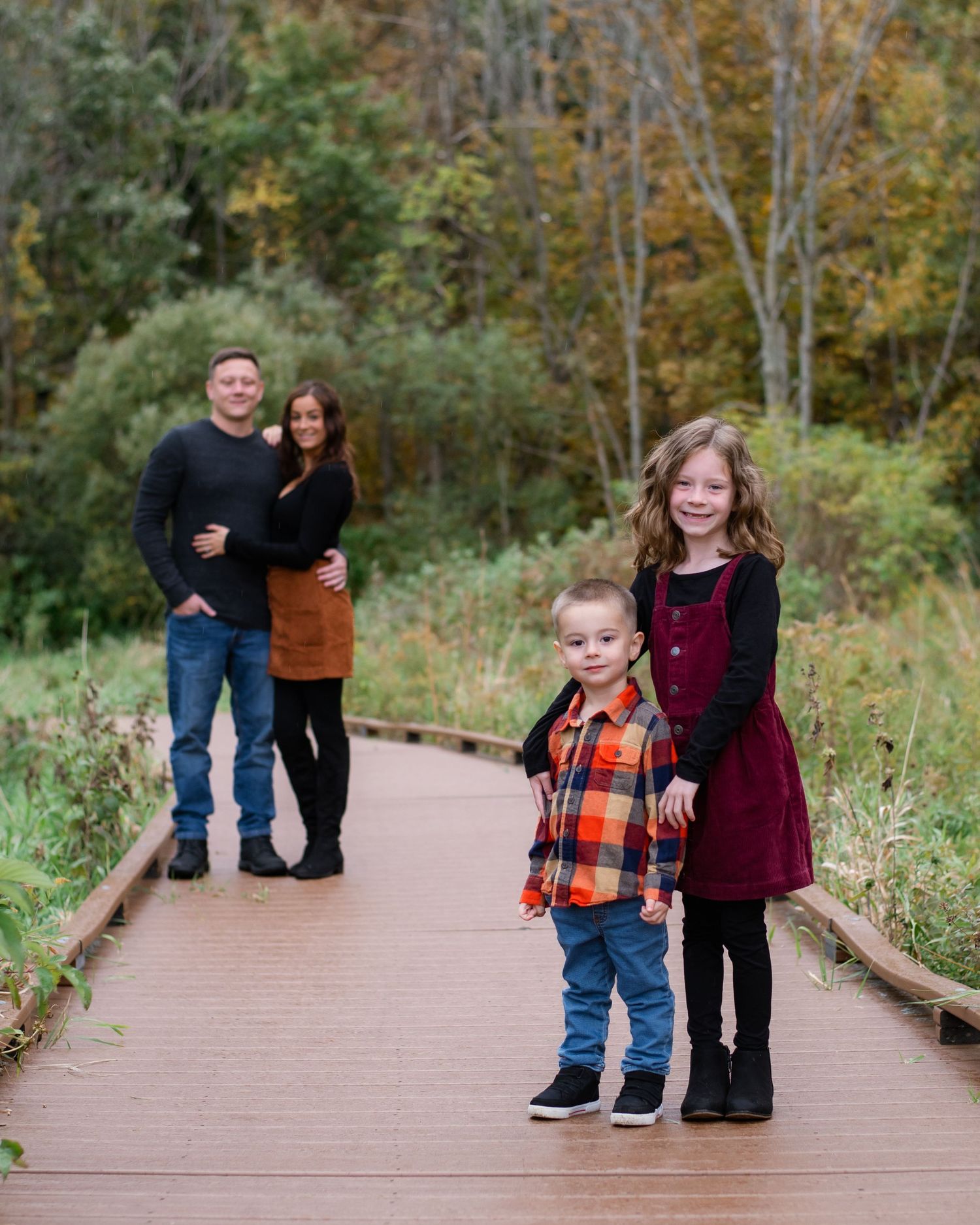 Family portrait on wooden boardwalk with children in foreground and parents in background.