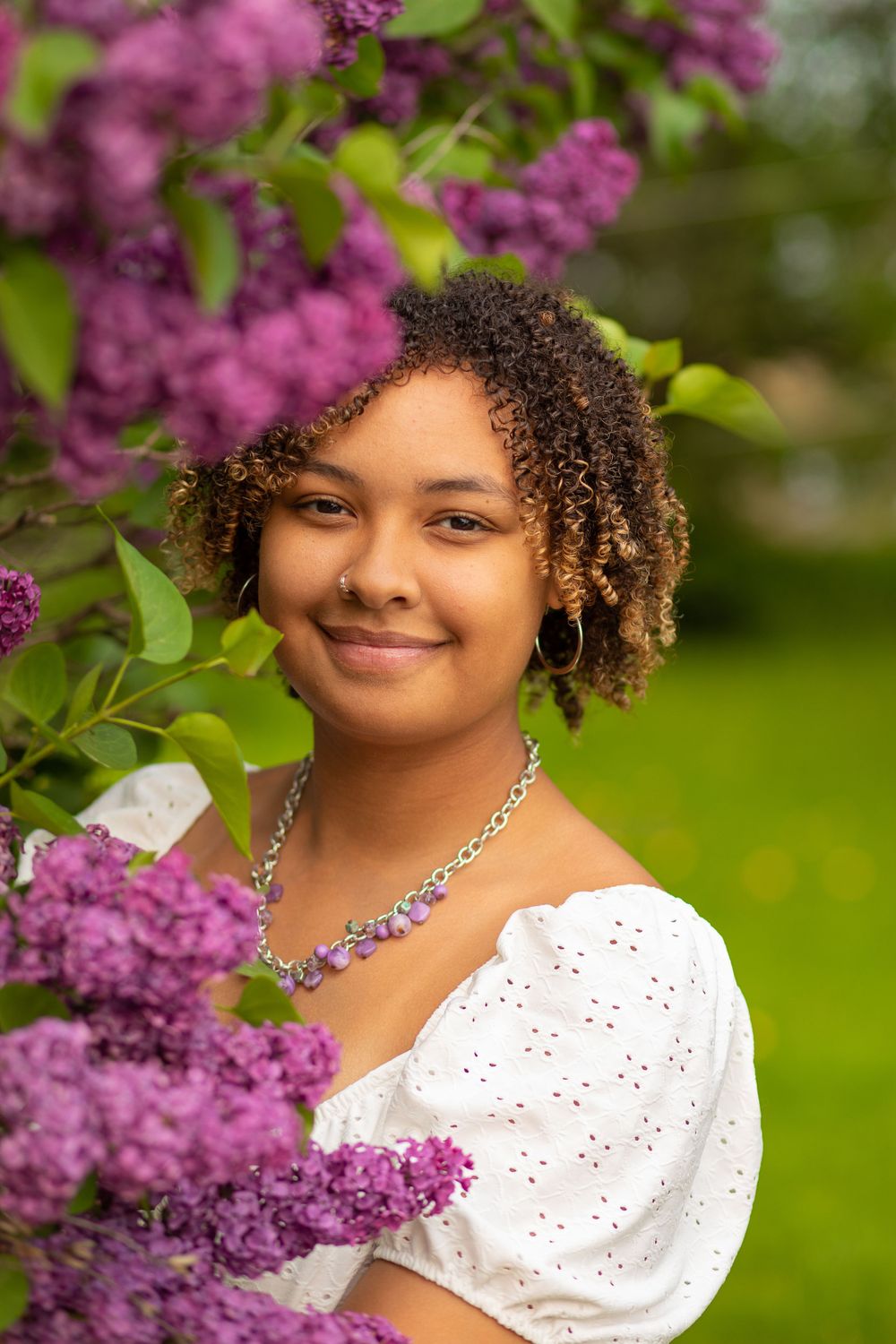 Portrait against blooming lilac bushes with purple flowers in springtime setting.