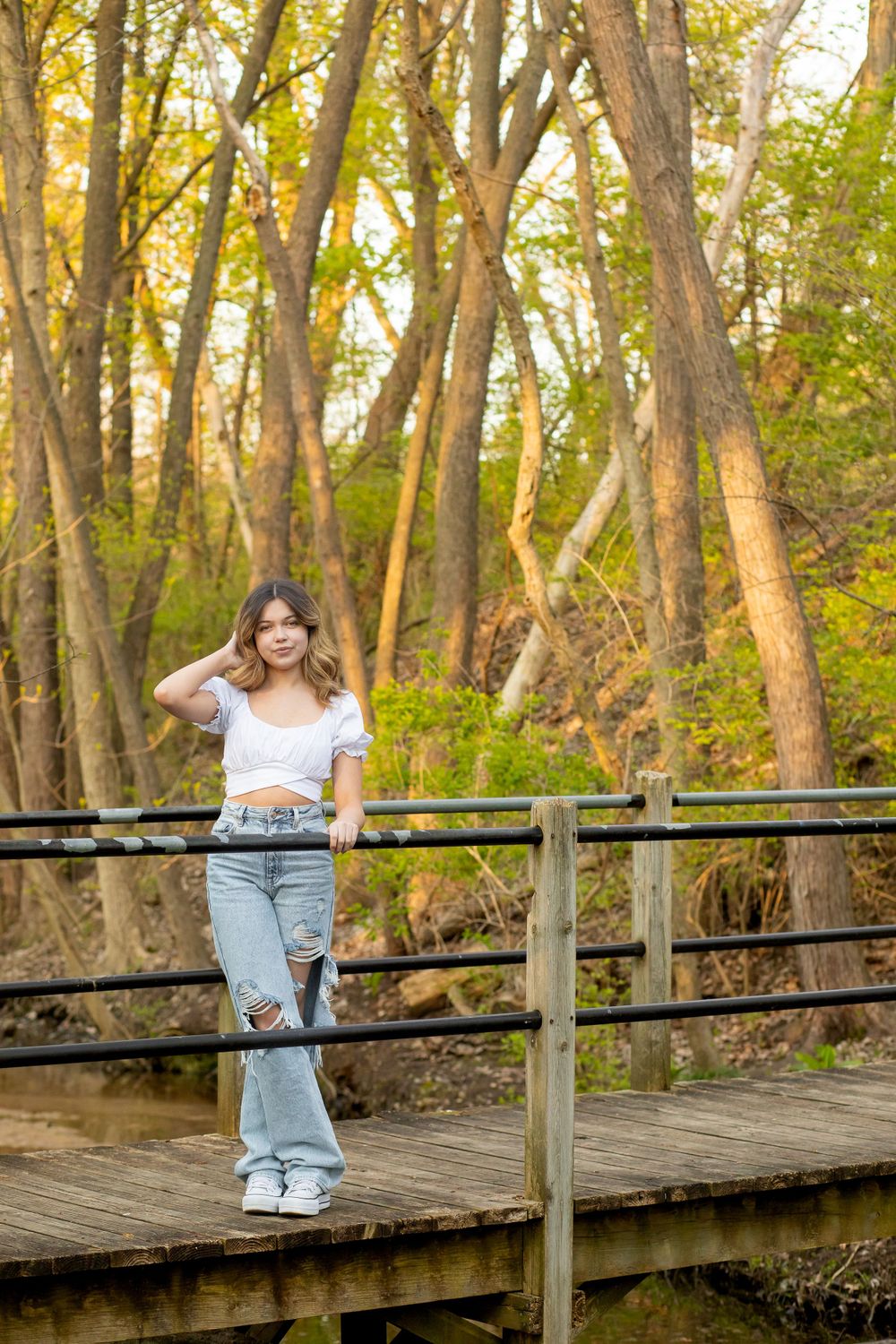 A sunny autumn portrait session on a wooden bridge in a forest setting.
