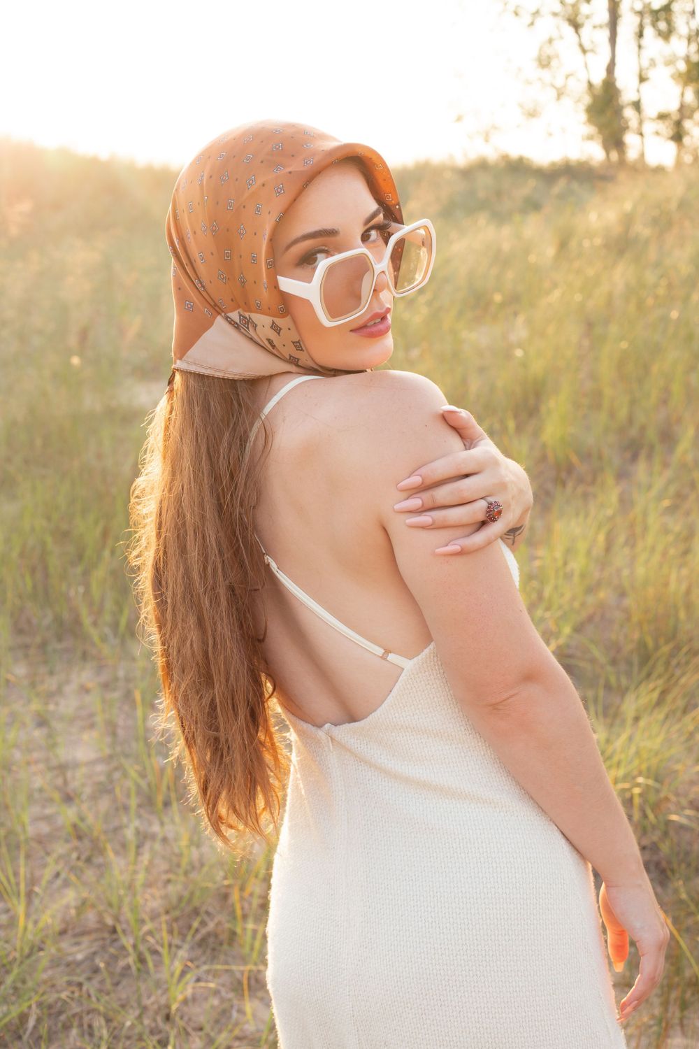 Lady with long hair and 70's sunglass by a field