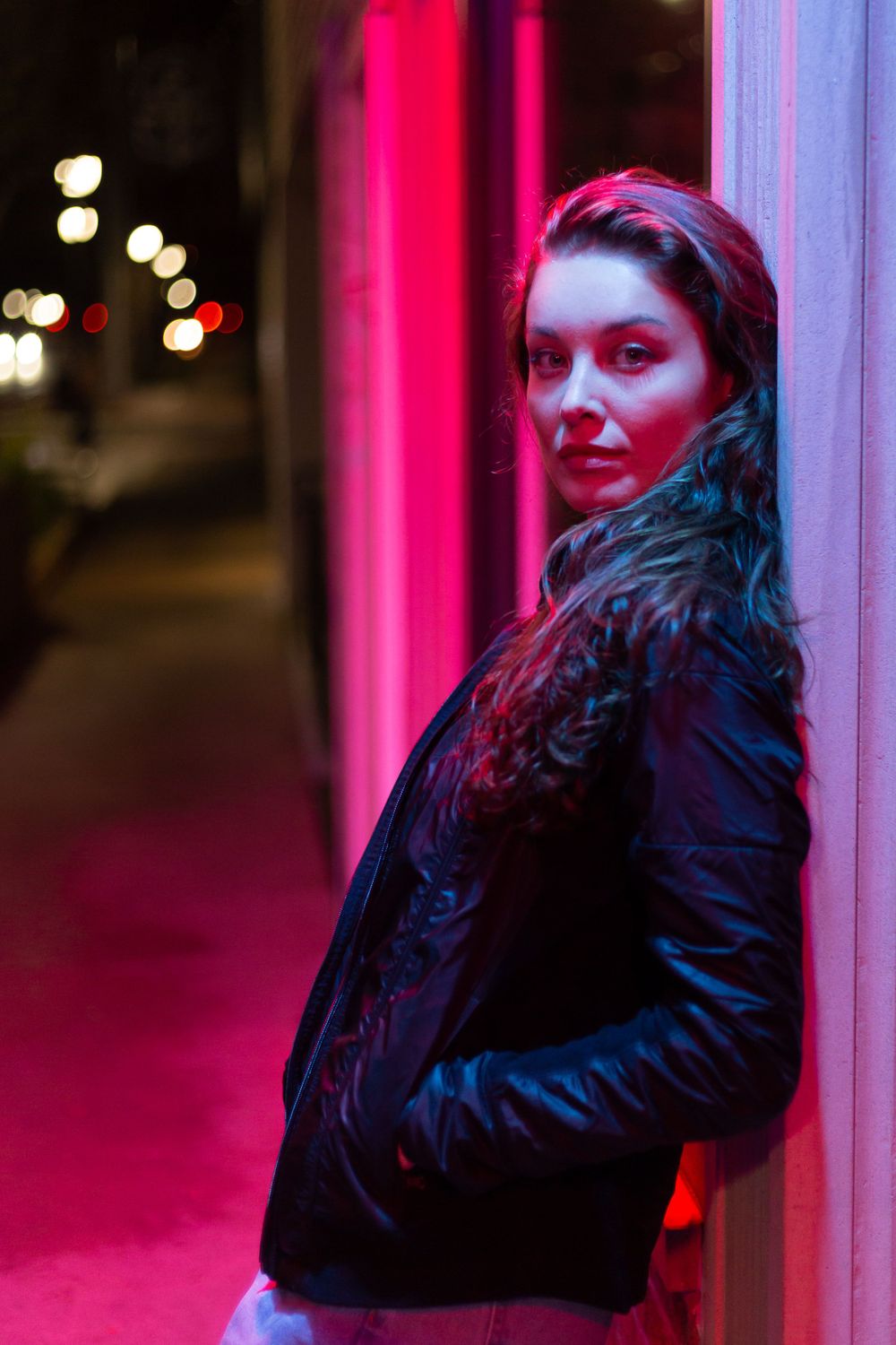 A moody nighttime portrait with pink neon lighting and a black leather jacket.