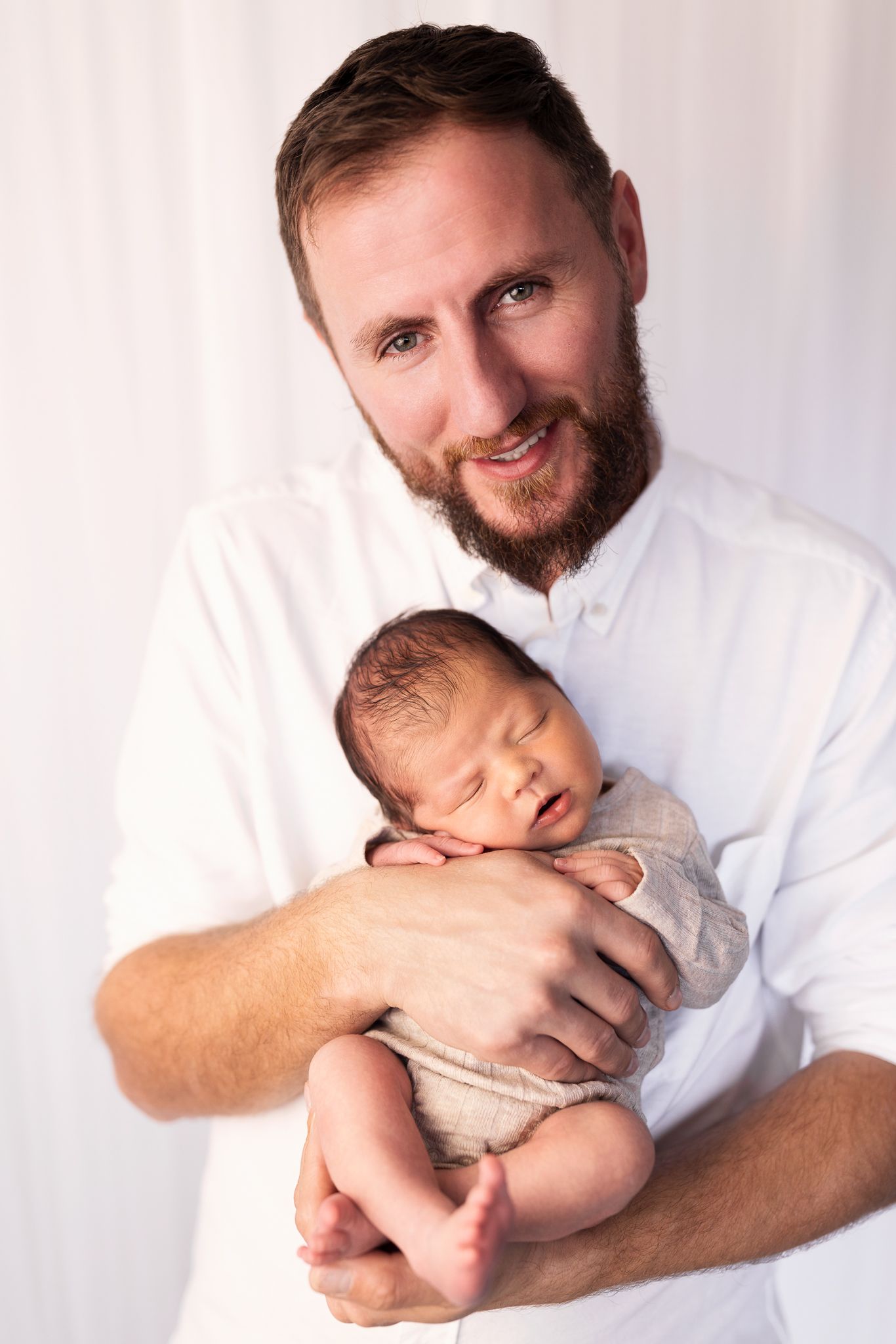 Tender newborn photography series showing gentle moments with baby in white setting.