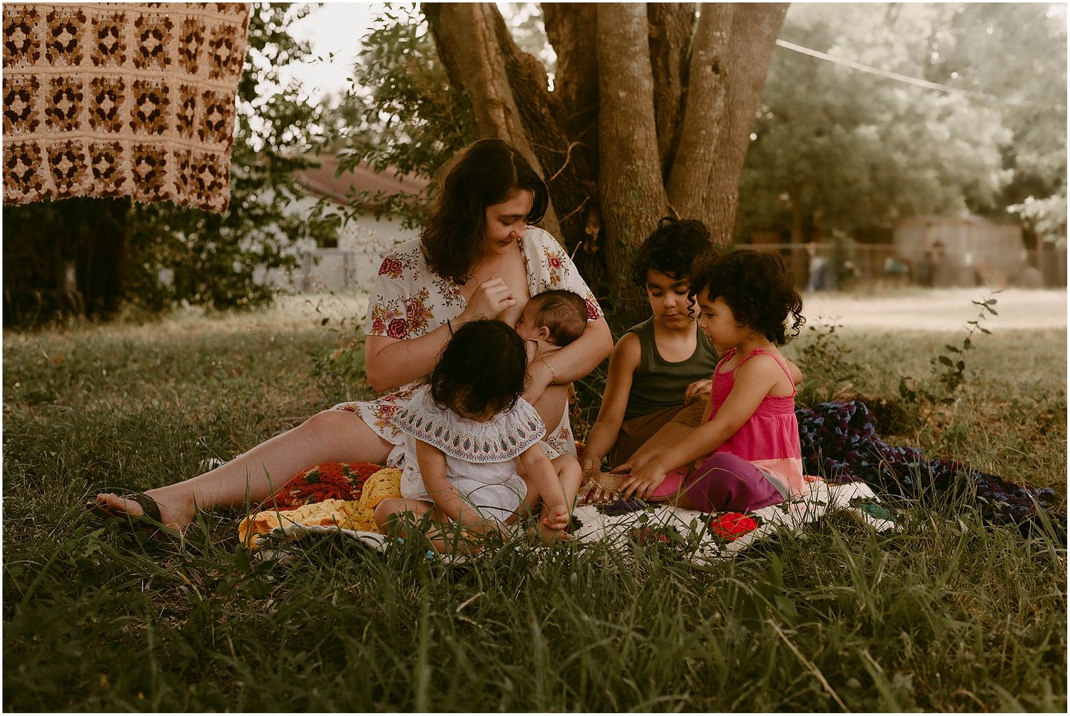A family relaxing together on a blanket in the grass during golden hour.