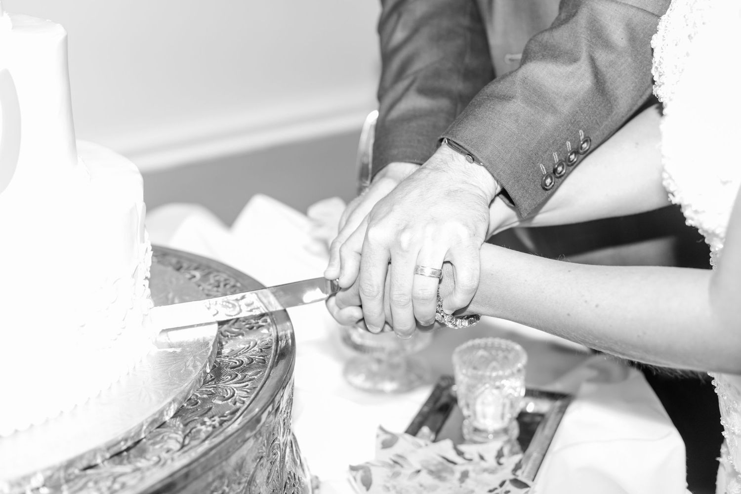 Close-up of traditional white wedding cake being cut during reception.