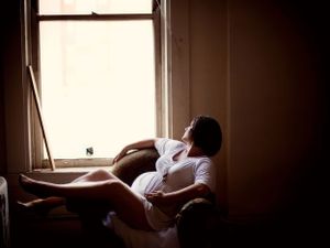 Pregnancy Portrait of a woman sitting in a chair and looking out the window.
