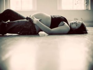 Maternity portrait of woman lying on the ground and looking at the camera.