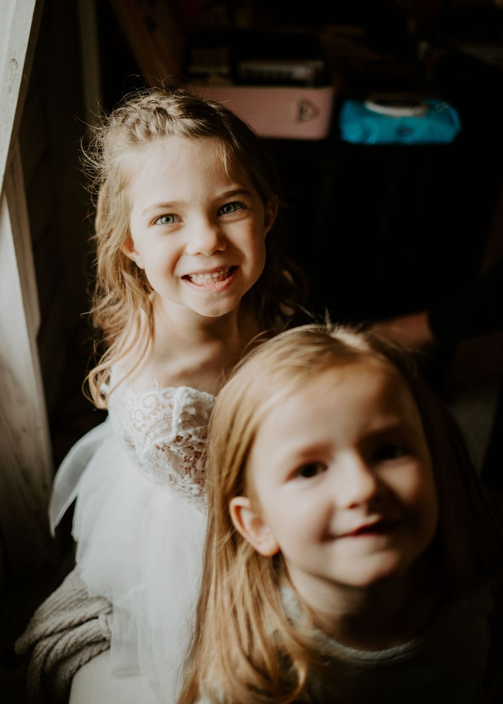 Two children in wedding attire pose in natural light.