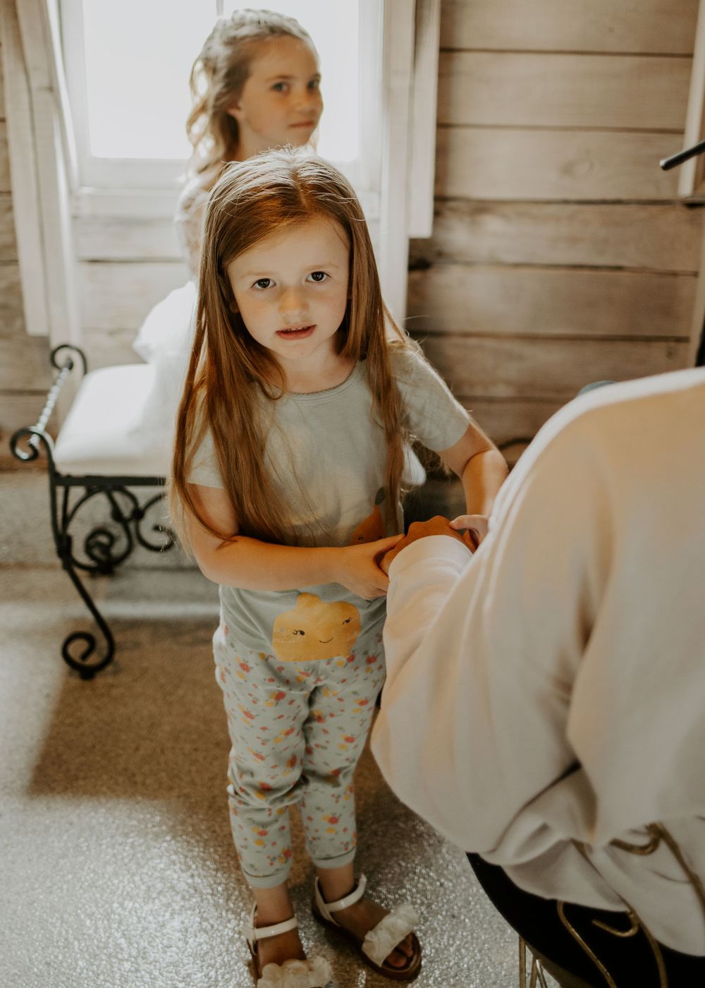 Young child in casual clothing stands in rustic indoor setting.