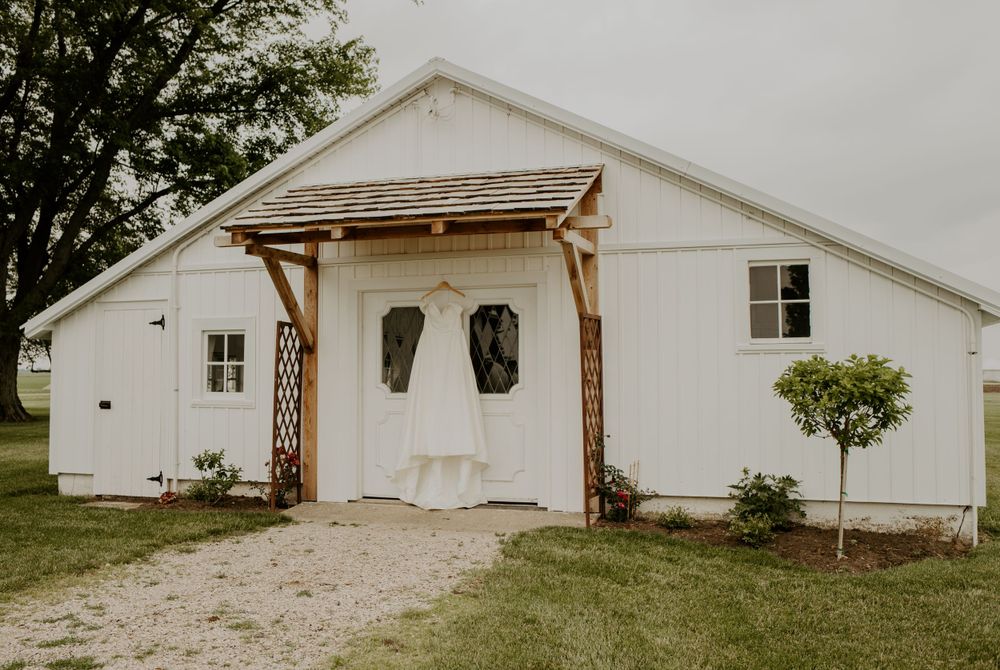 White rustic barn-style building with wooden awning and gravel pathway.