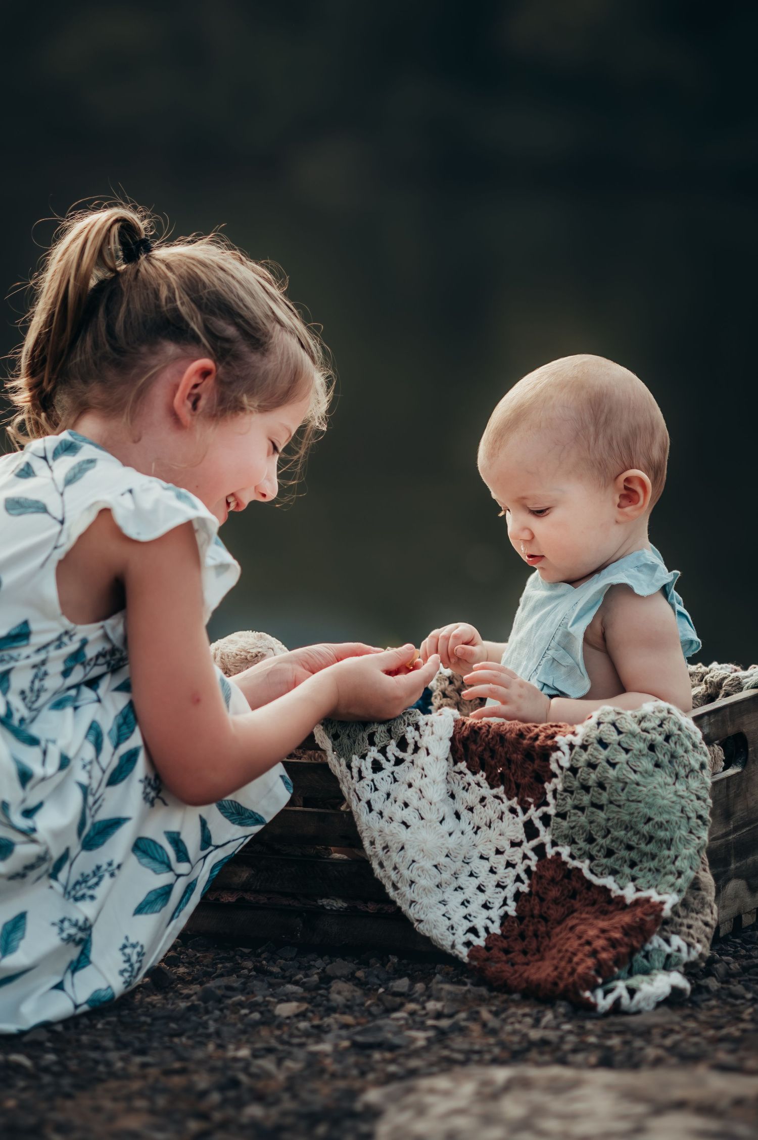little girl shows her baby sister some shells the found while exploring at their family photo session in Chattanooga