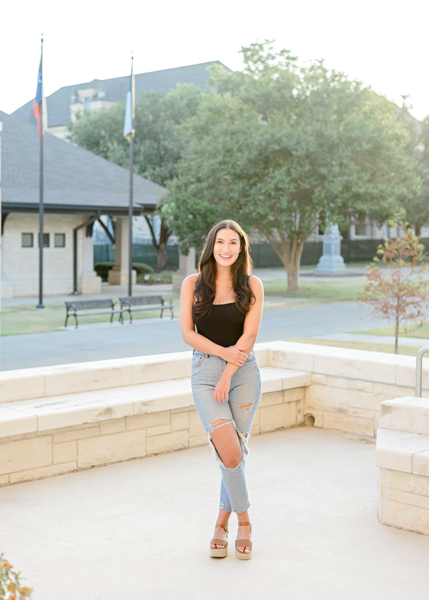 Casual outdoor portrait with urban architecture and landscaping creating modern aesthetic.