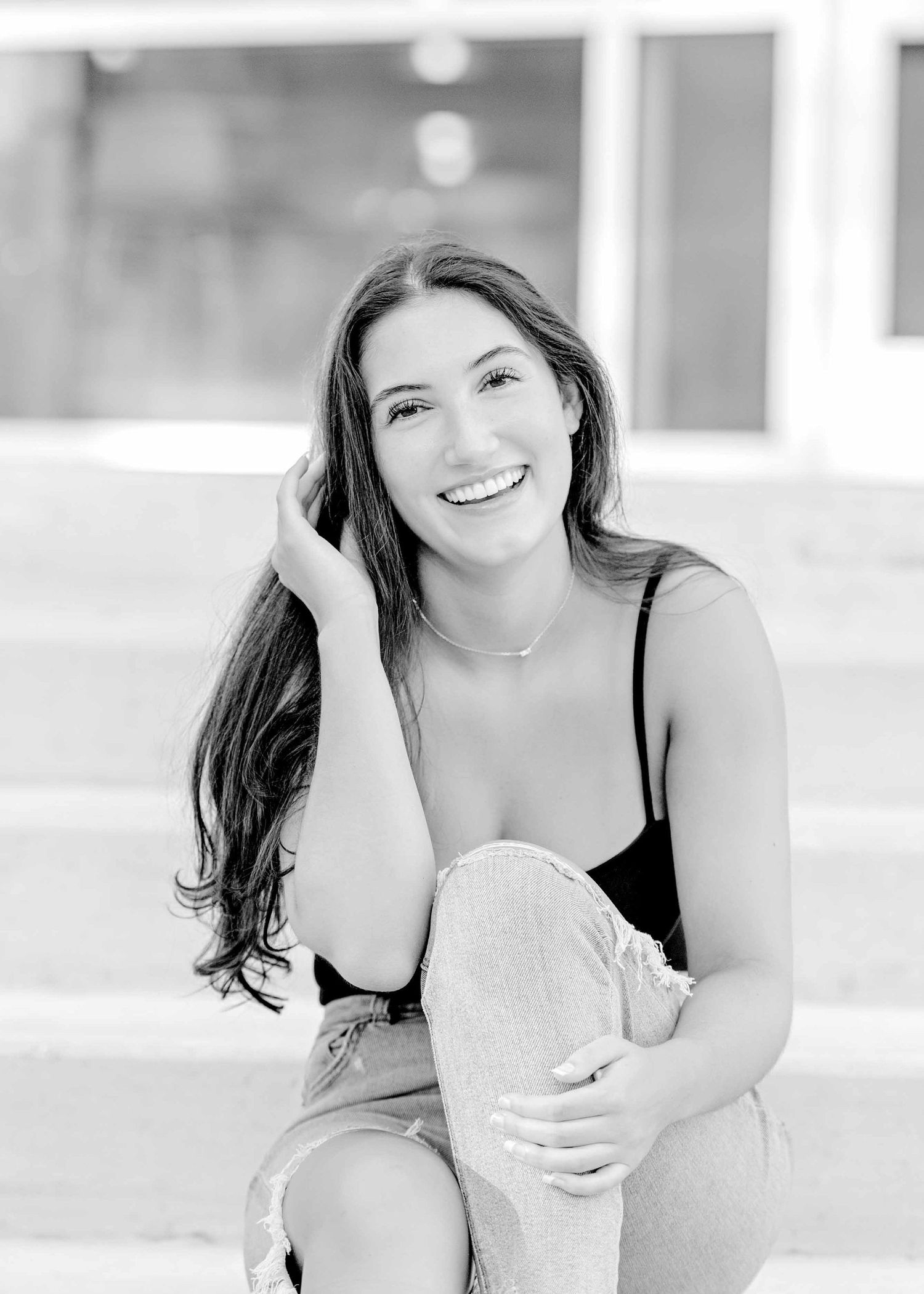 Black and white portrait with natural expression while sitting on outdoor steps.