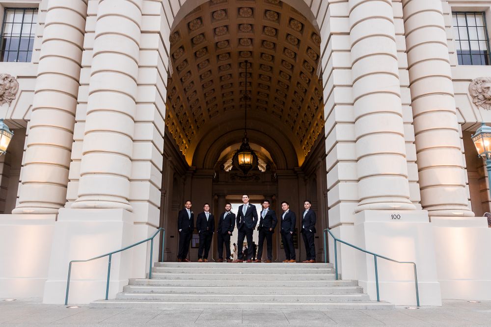 groom and groomsmen  standing in archway of the pasadena city hall