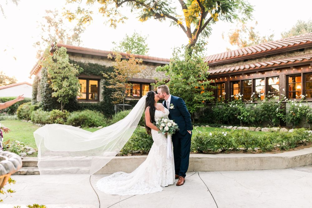 Bride and groom kissing with brides veil blowing in the wind