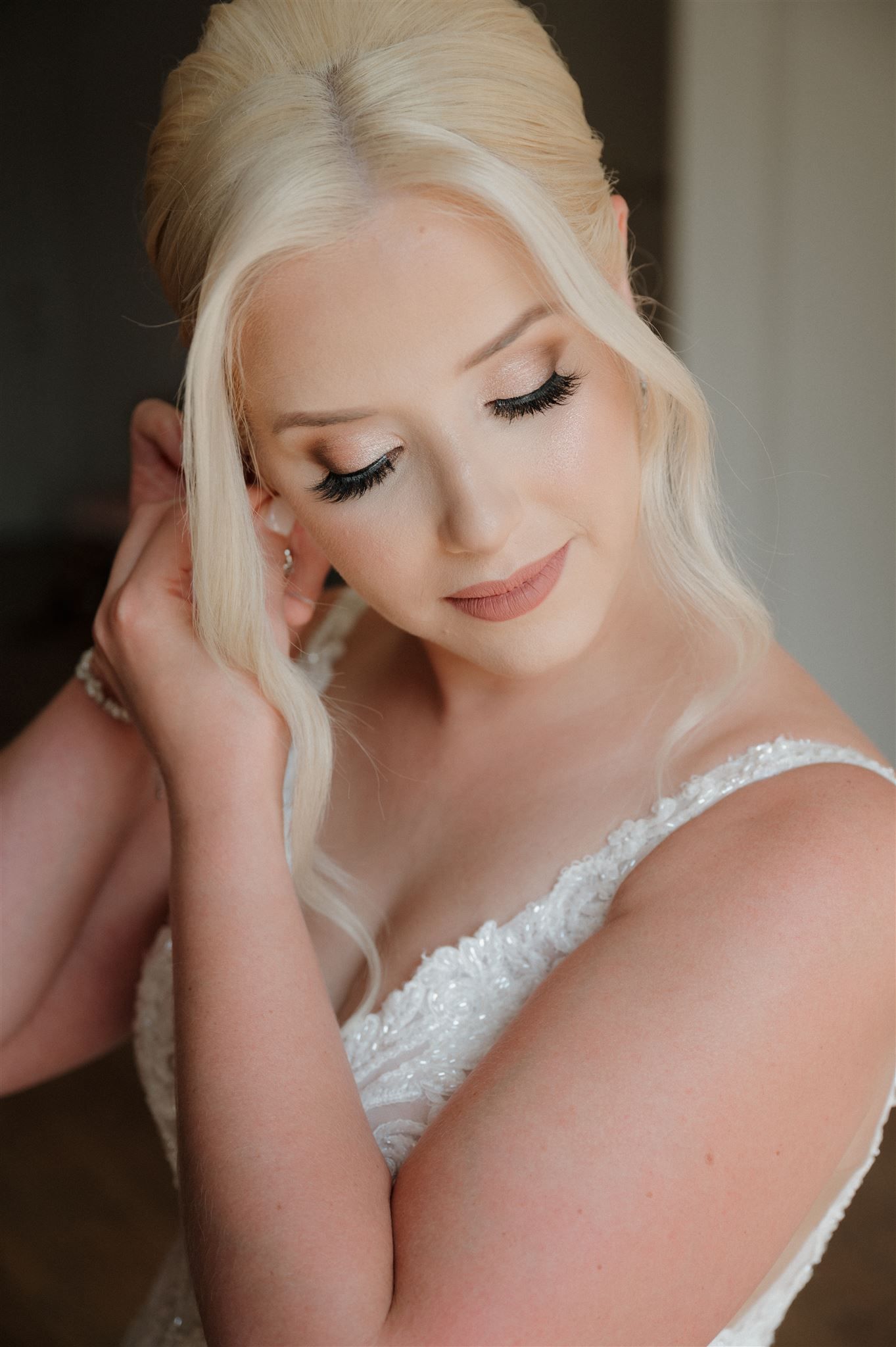Soft bridal beauty portrait featuring romantic makeup and lace dress detail.