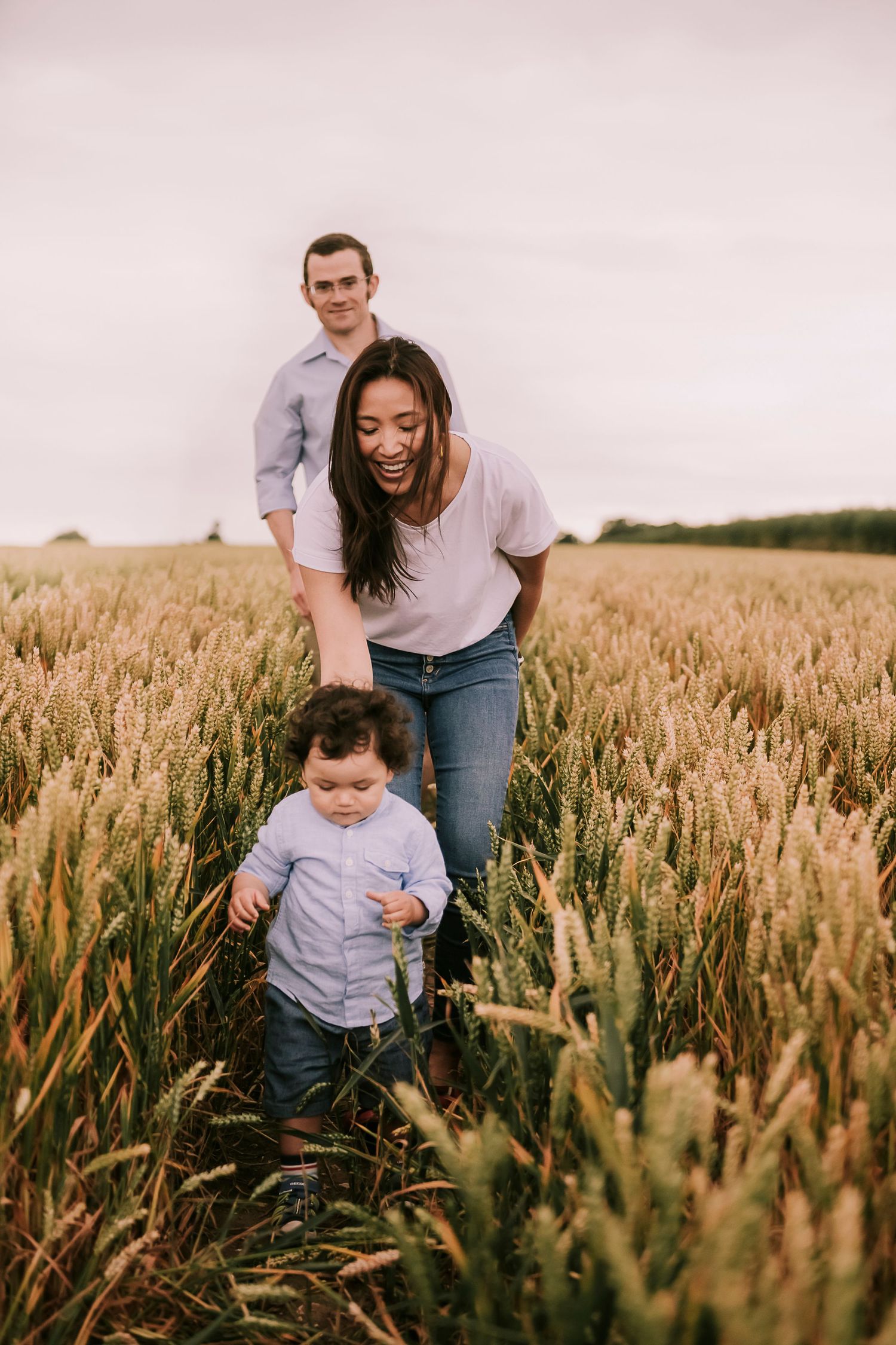 Happy family enjoying a playful moment together in a golden wheat field at sunset.