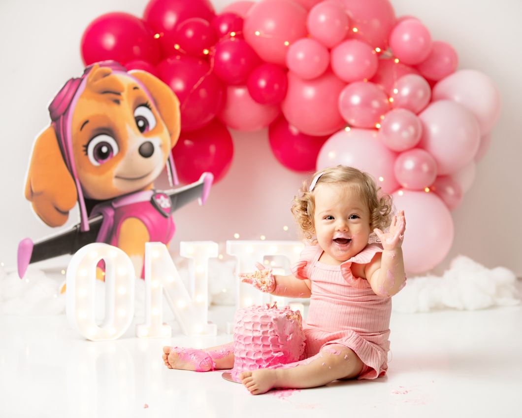 Birthday party setup with pink balloon arch and Paw Patrol decorations. best cake smash photogpgrapher